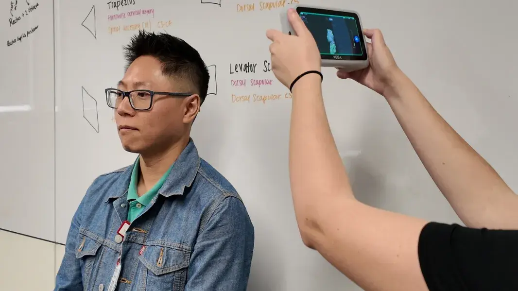 A person using a Einstar Vega handheld 3D scanner to scan a participants head.