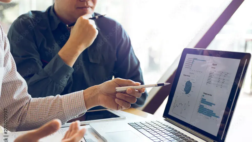 Two people looking at data on a laptop